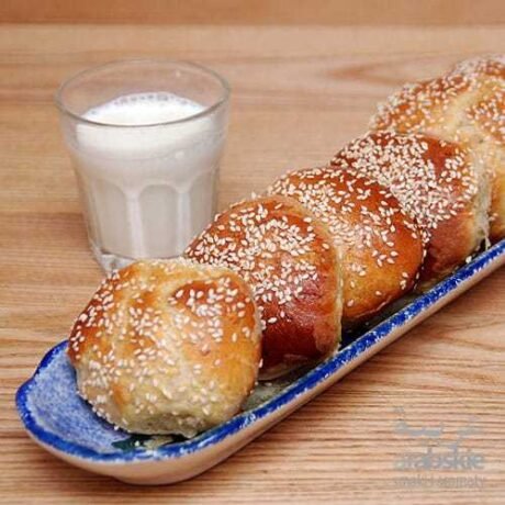 arabskie drożdżowe bułeczki z melasą i przyprawą do ciasta kaak, posypane białym sezamem podane z ayranem
