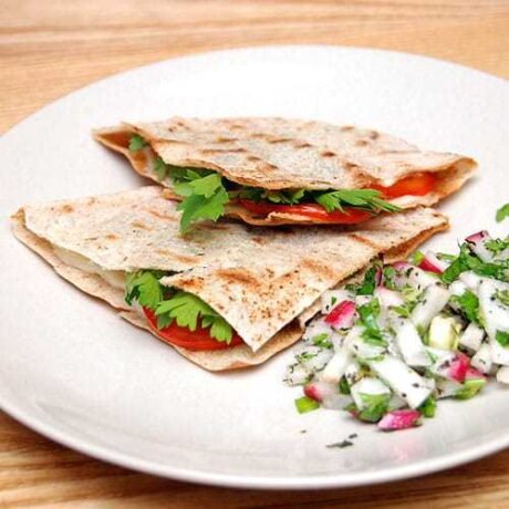 kawałki sera halloumi, plasterki czerwonego pomidora i świeża natka pietruszki, zawinięte w trójkąciki z pełnoziarnistej pity, zapieczone na patelni grillowej