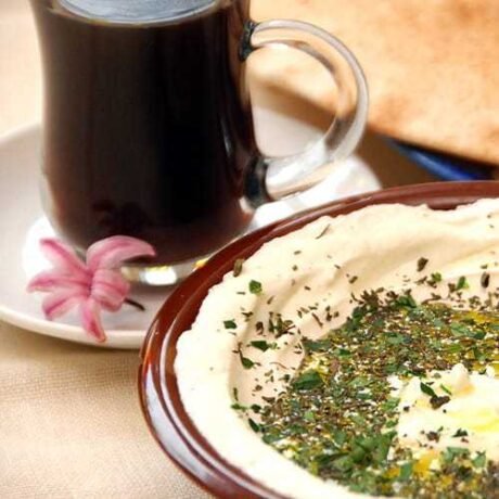 arabski hummus w tradycyjnej ceramicznej miseczce opruszony świeżą natką pietruszki i oliwą z oliwek z herbatą po beduińsku