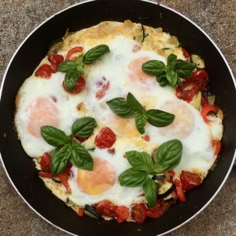 arabska szakszuka z cukinią, papryką, pomidorkami koktajlowymi i świeżą bazylią podane na patelni