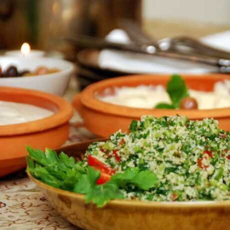 arabska sałatka tabbouleh w szklanej miseczke udekorowana pomidorkami koktajlowymi i natką pietruszki